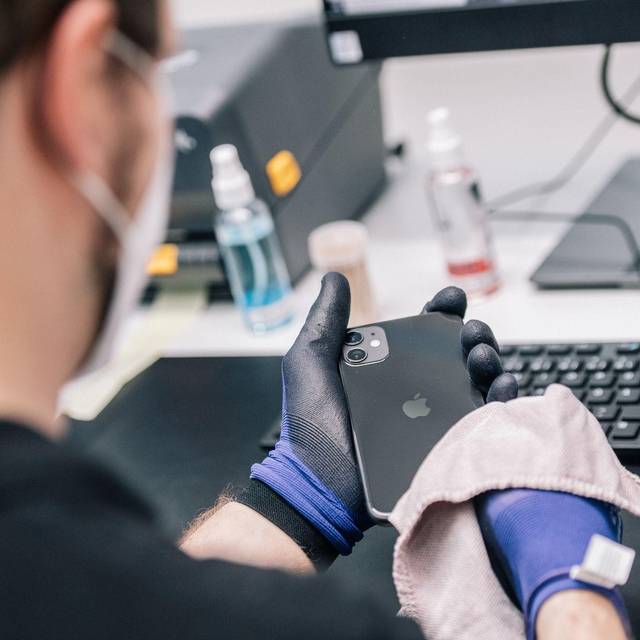 Ein Mitarbeiter überprüft ein refurbished Iphone