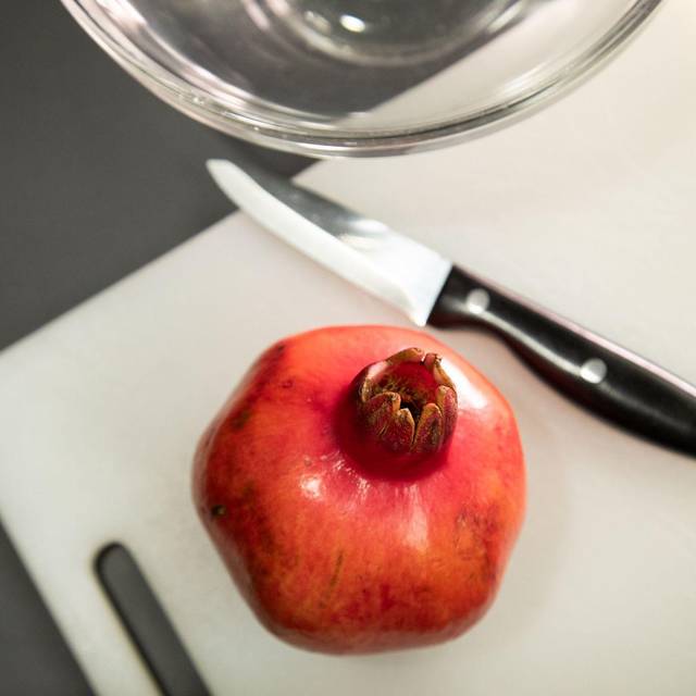 Granatapfel liegt neben einem Messer auf einem Tisch