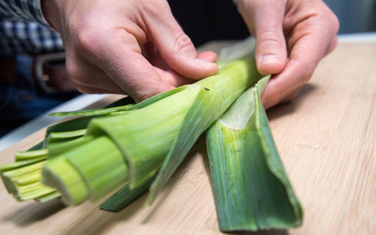 Mann entfernt die äußeren Blätter einer Lauchstange