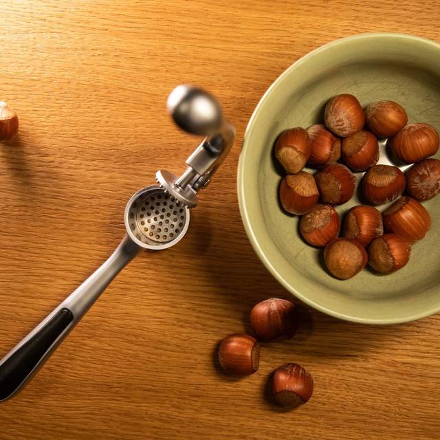 Haselnüsse liegen neben einer Knoblauchpresse