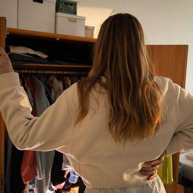 Eine Frau steht vor ihrem geoeffneten Kleiderschrank