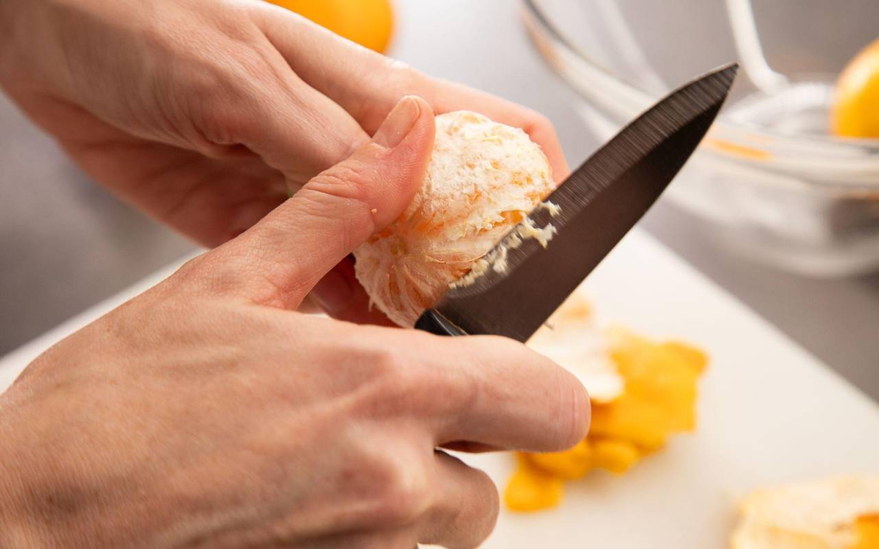 Eine Clementine wird mit einem Messer geschält