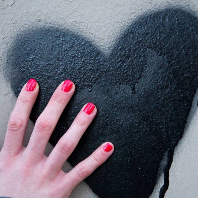 Frauenhand berührt ein auf die Wand gesprühtes Herz