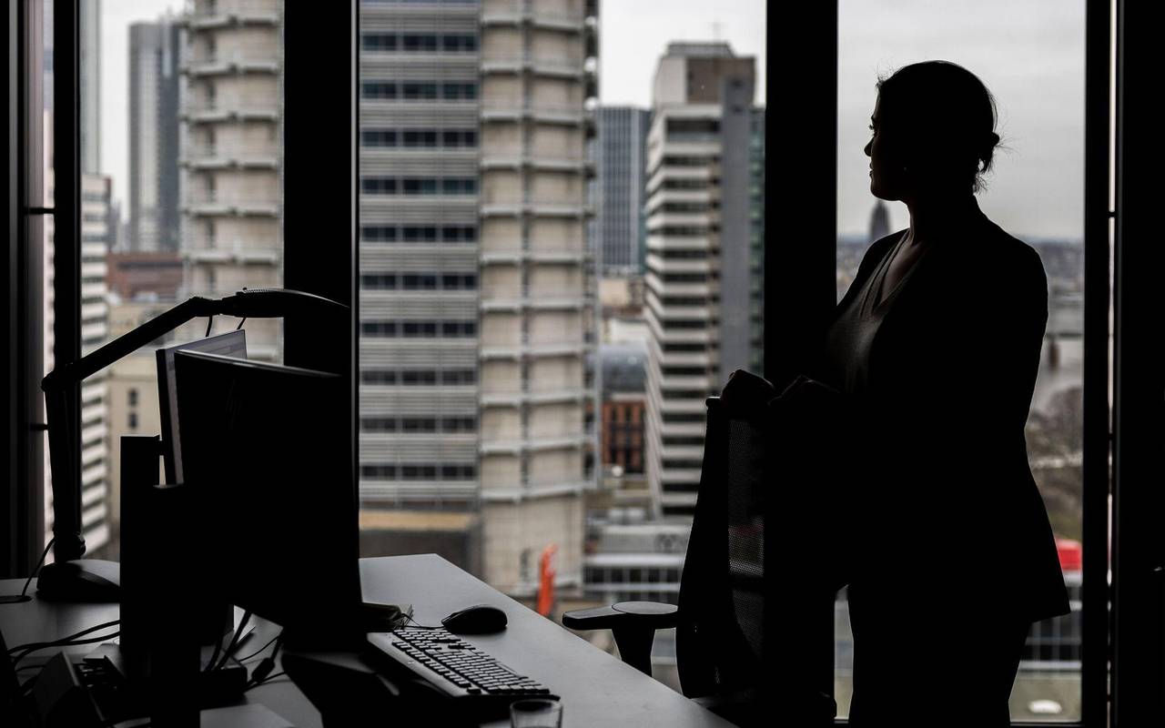 Frau steht an ihrem Arbeitsplatz am Fenster