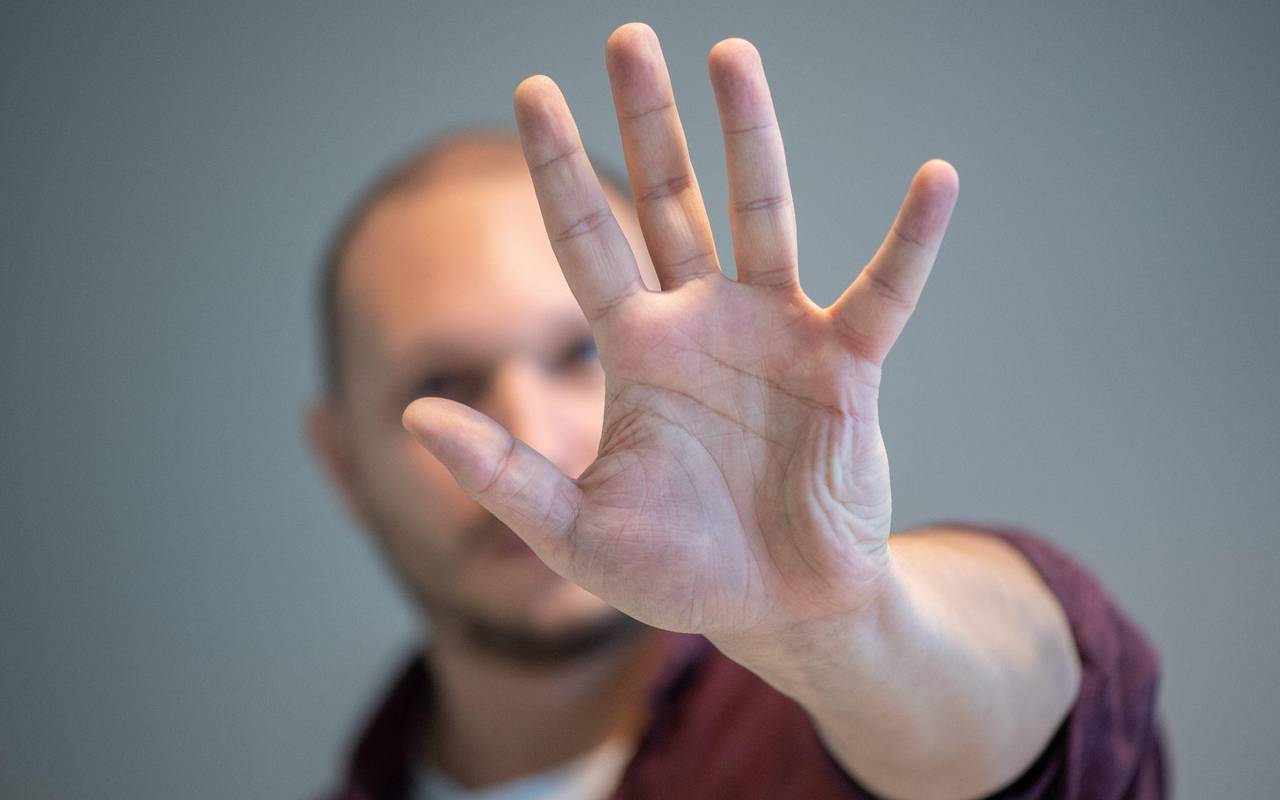 Ein Mann hebt schützend die Hand vor sein Gesicht