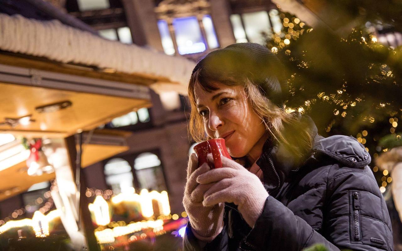 Frau trinkt auf dem Weihnachstmarkt ein Heissgetränk