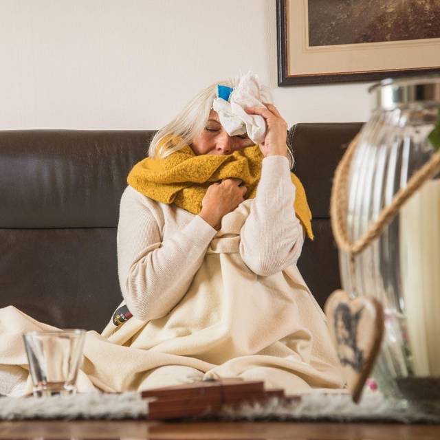 Eine Frau mit einer Erkältung auf einem Sofa