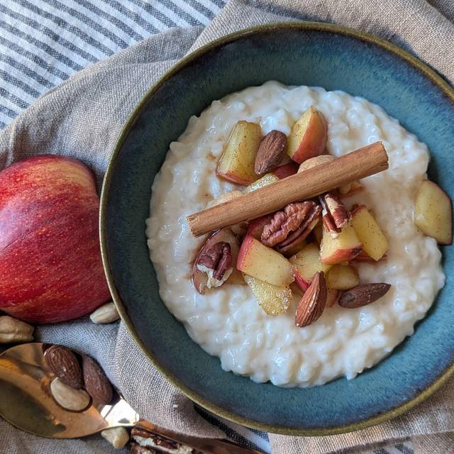 Milchreis mit Apfel, Zimt und Nüssen steht auf einem Tisch