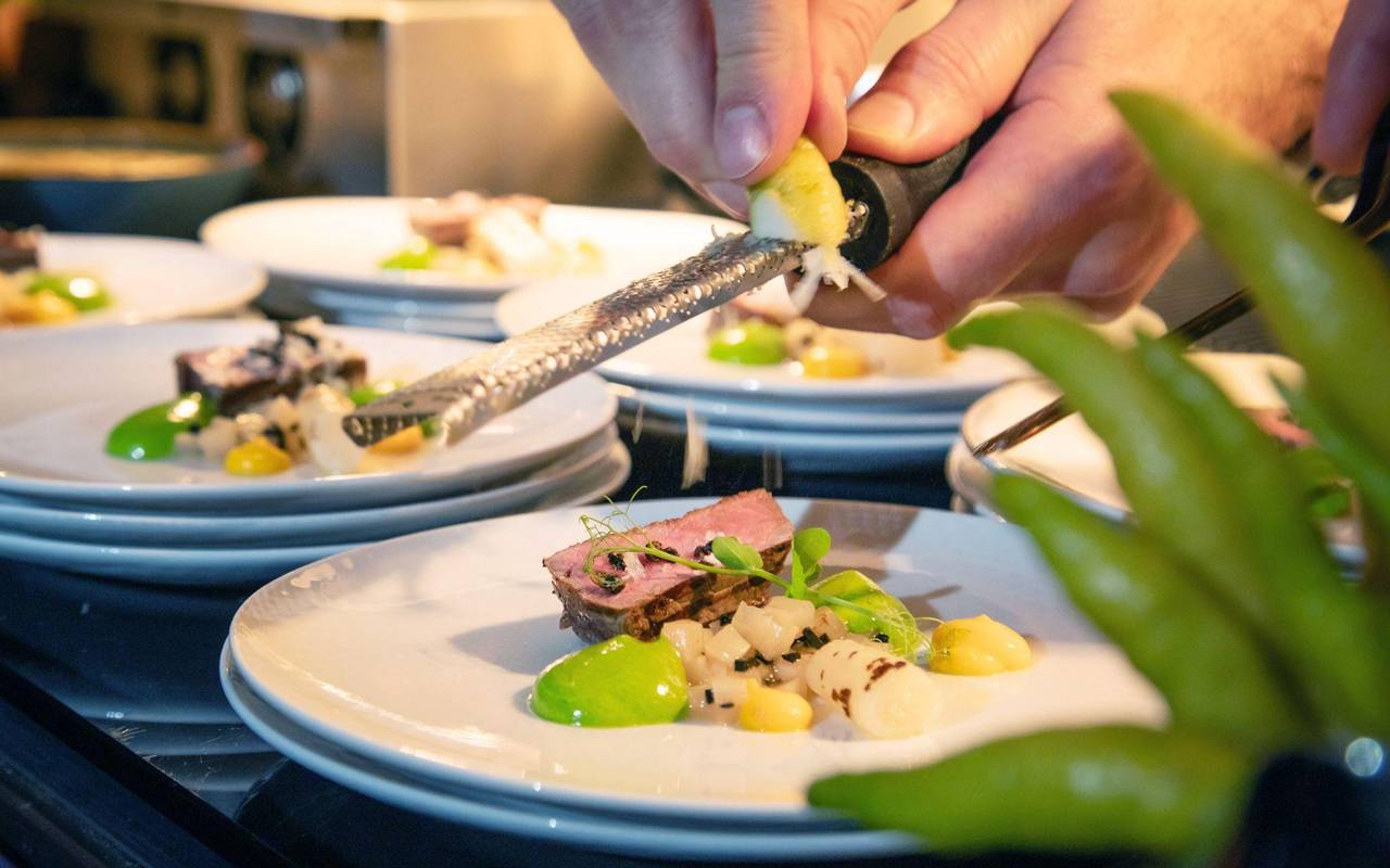 Koch reibt Zesten der Zitrusfrucht Buddhas Hand über ein Menü