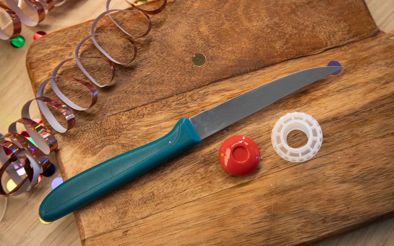 Ein Messer neben einem aufgeschnittenen Plastiksektkorken