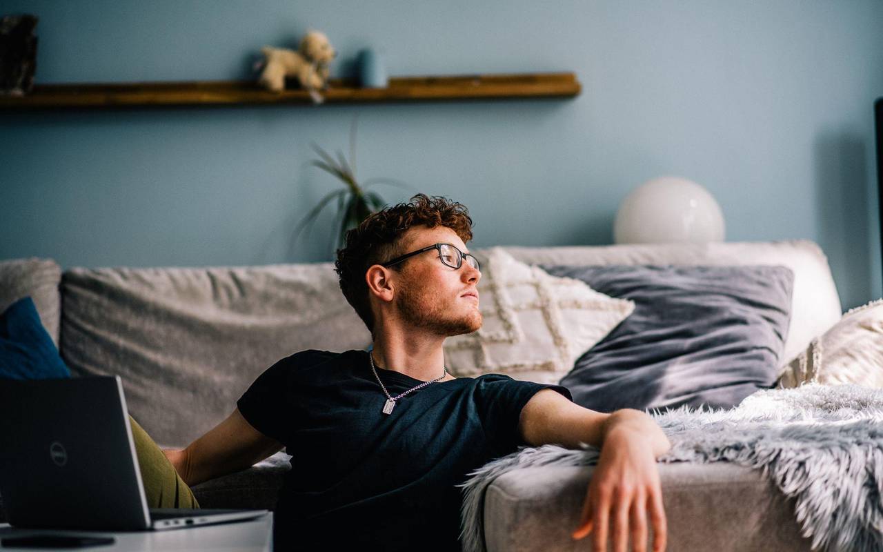 Ein junger Mann sitzt auf dem Boden vor seinem Computer