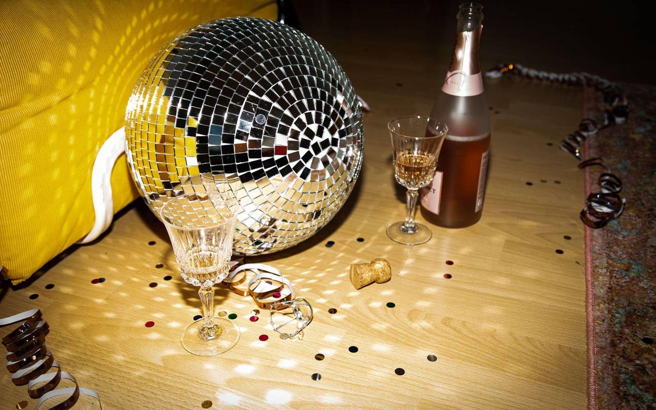 Discokugel liegt neben Sektflaschen und Gläsern auf dem Boden