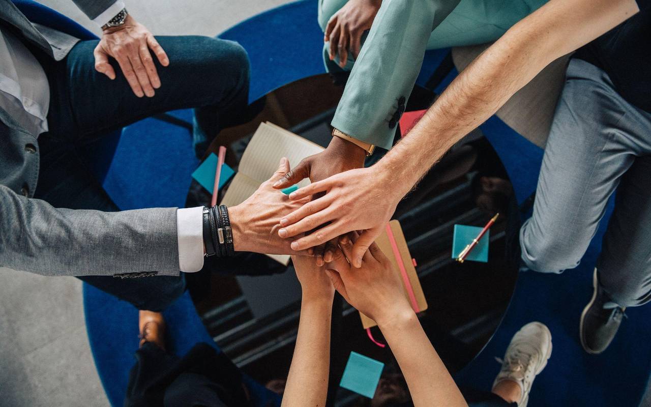 Gruppe Kolleginnen und Kollegen legen die Hände aufeinander