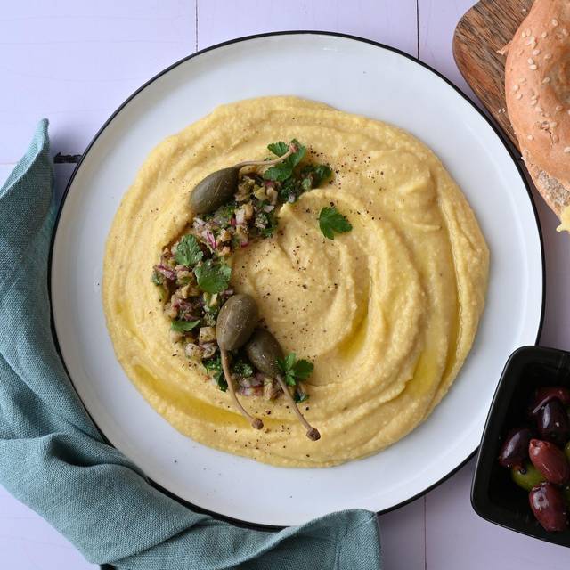 Ein Teller Linsendip, ein Bagel und eine Schale Oliven