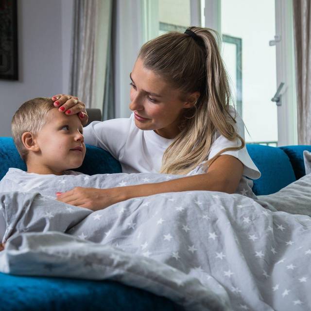 Eine Mutter kümmert sich um ihr kranken Kind mit Fieber