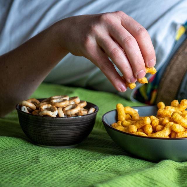 Mann isst auf einem Sofa Chips