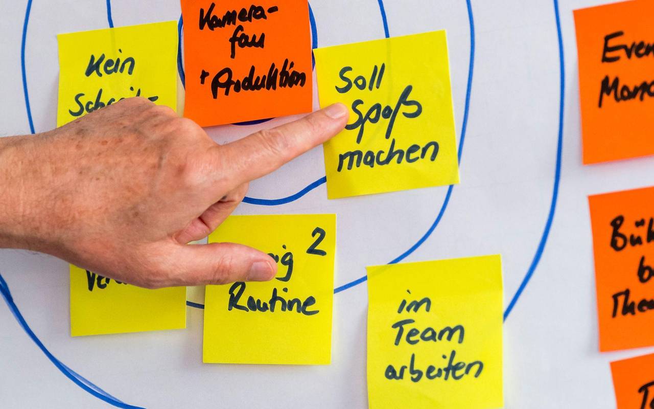 Eine Person klebt Post-its auf ein Flipchart