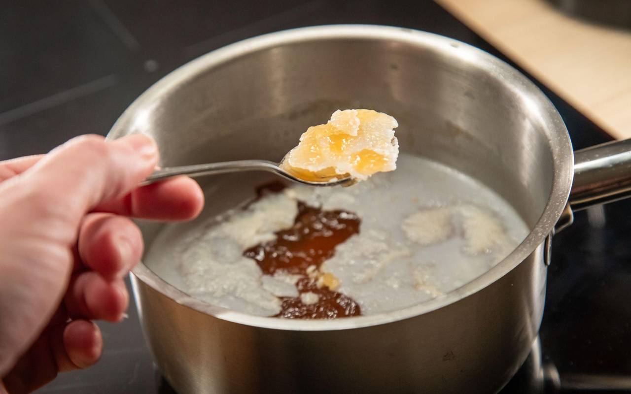 Fett wird mit einem Löffel von einer Brühe geschöpft