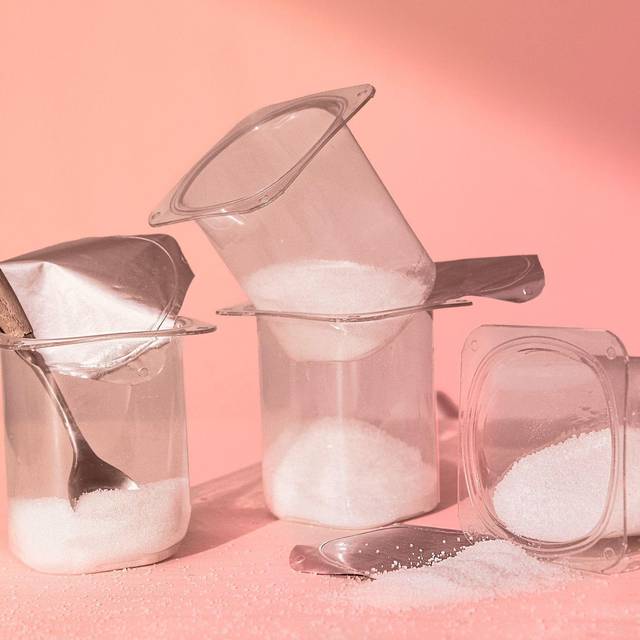 Mit Zucker gefüllte Joghurtbecher stehen auf einem Tisch