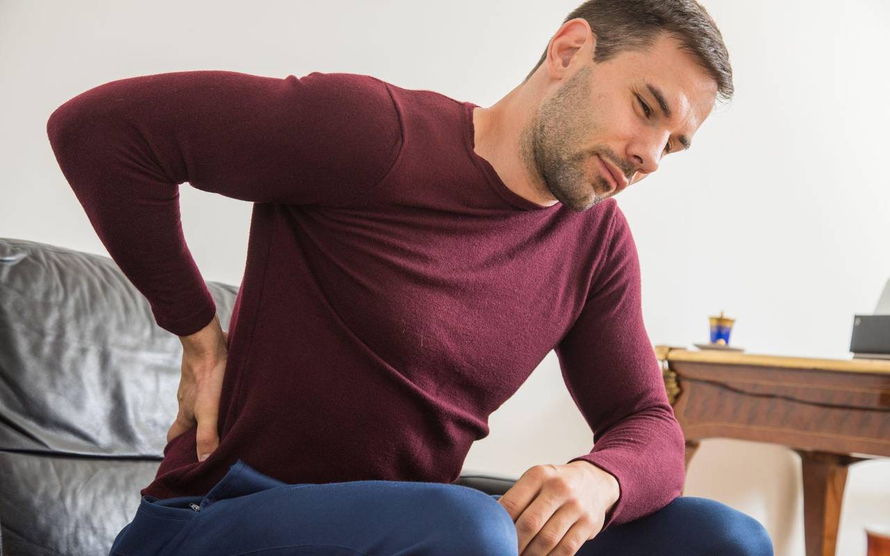 Ein Mann hält sich den unteren Rücken