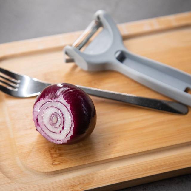 Zwiebel und ein Sparschäler liegen auf einem Tisch