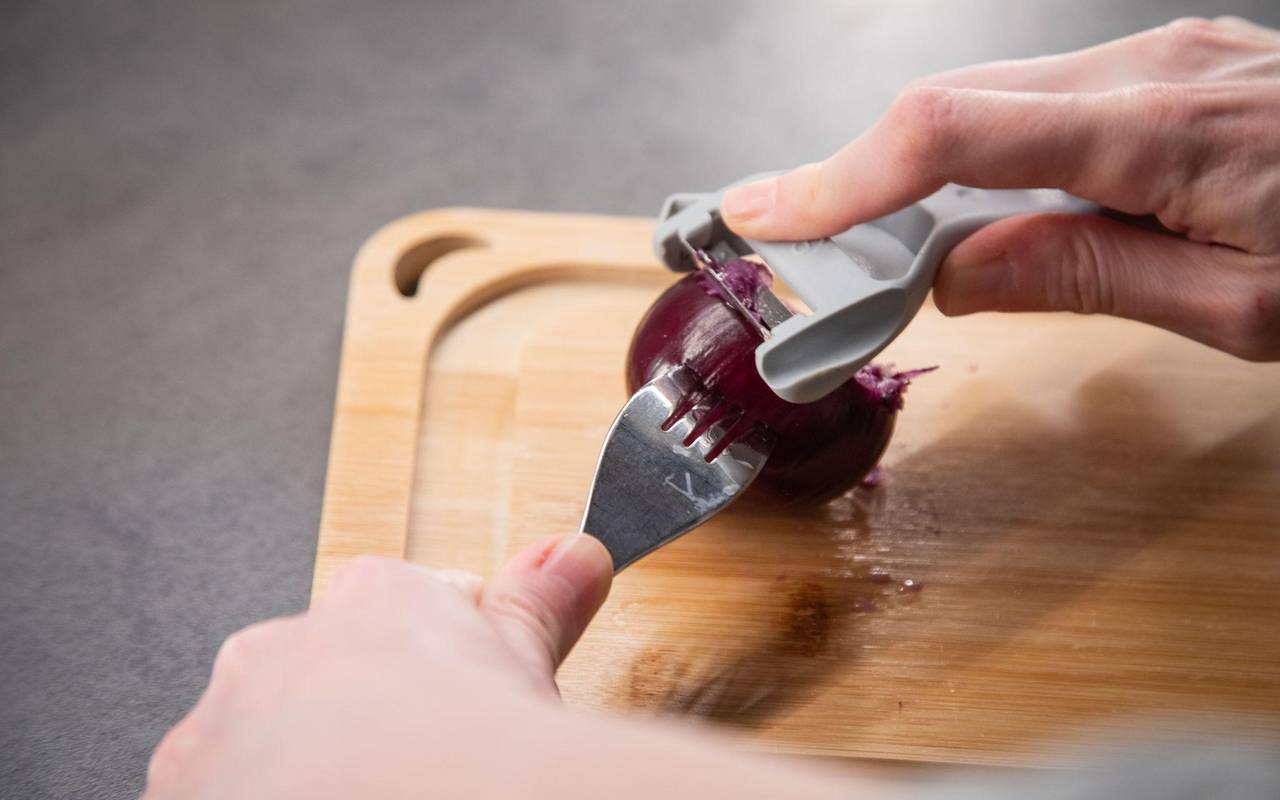 Ein Sparschäler wird über eine Zwiebel gezogen
