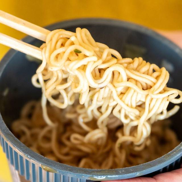 Eine Frau hält einen Becher Instantnudeln in der Hand