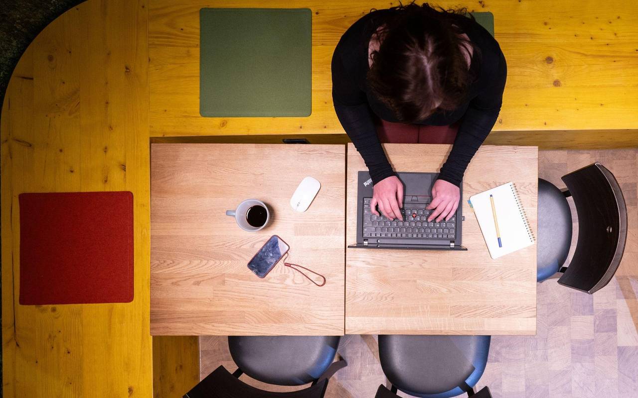 Frau sitzt im Homeoffice am Küchentisch und arbeitet am Laptop