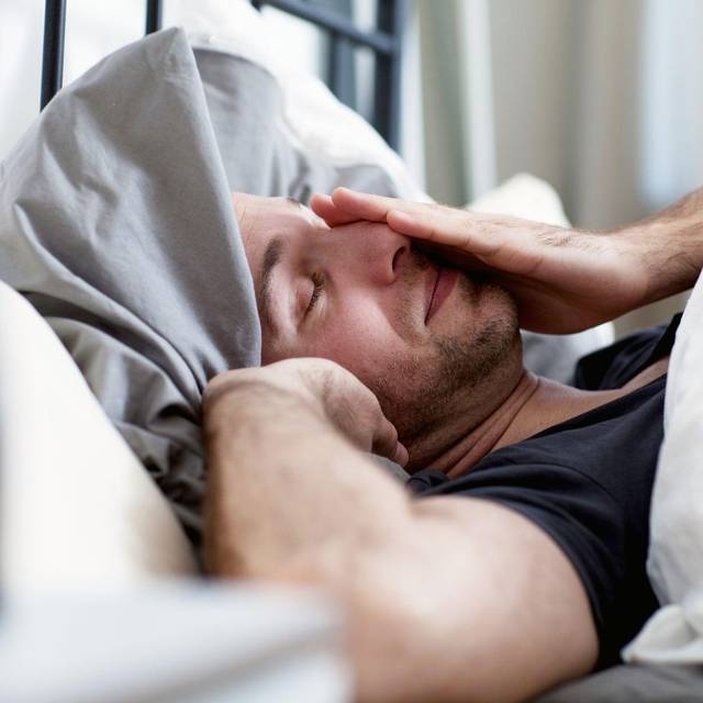 Ein Mann liegt verschlafen im Bett