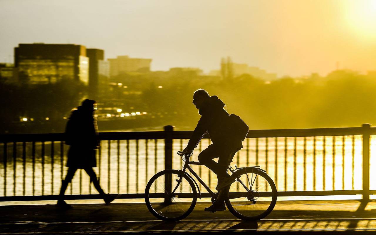 Fahrradfahrer fährt im Sonnenuntergang über eine Brücke