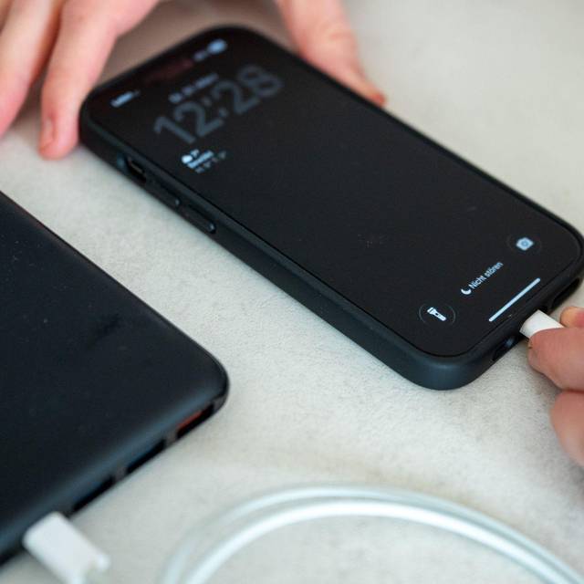 Eine Frau schließt ein iPhone an eine Powerbank an