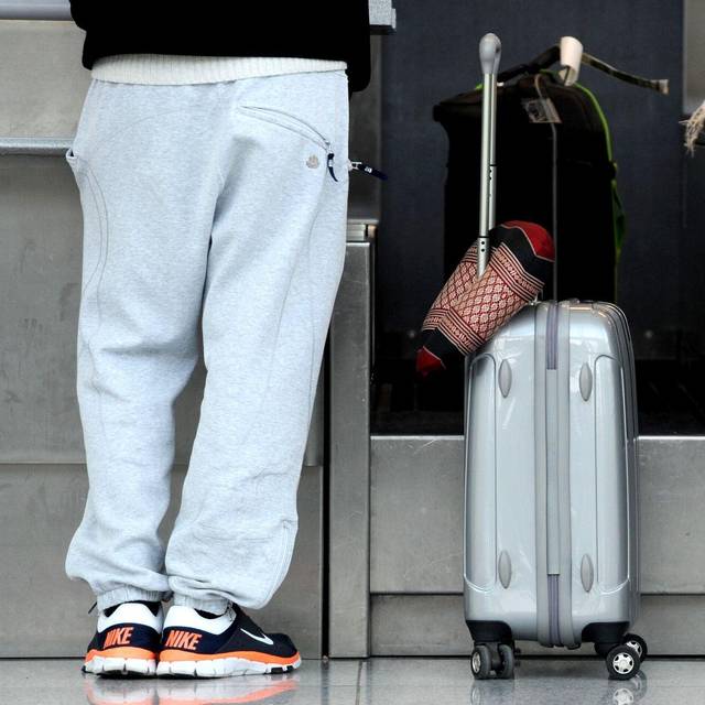 Ein Passagier in Jogginghose steht bei der Gepäckabgabe