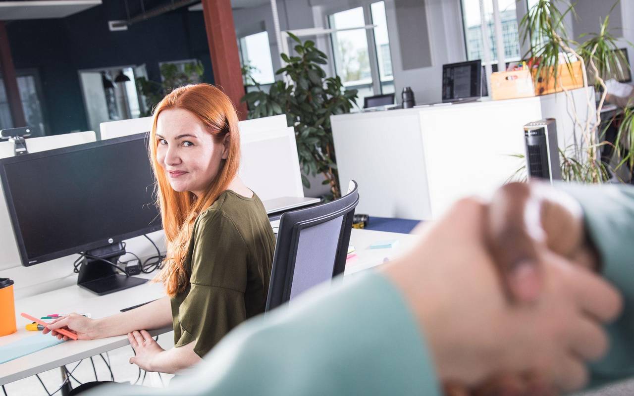 Kollegen reichen sich im Büro die Hände