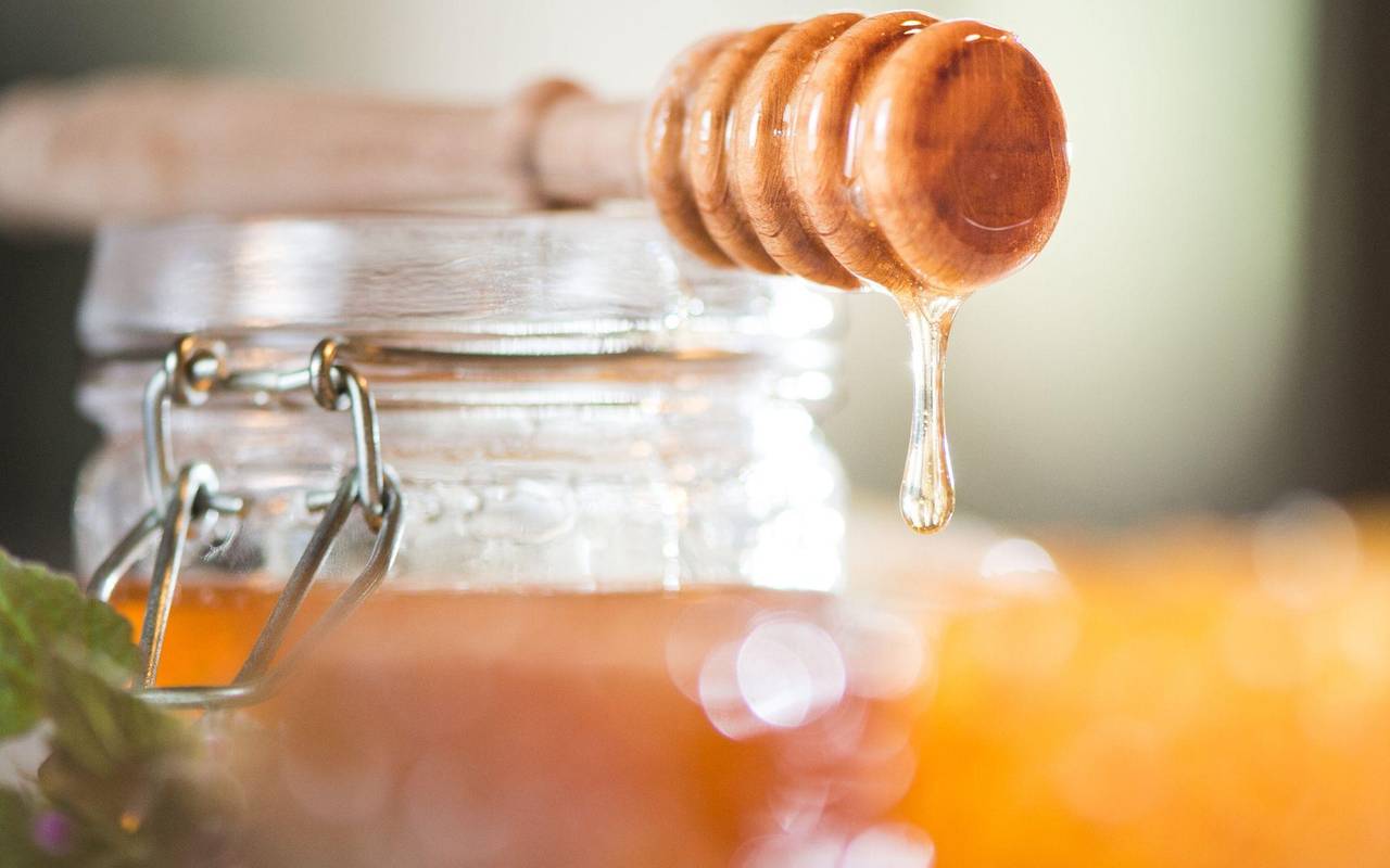 Honig tropft von einem Honiglöffel aus Holz