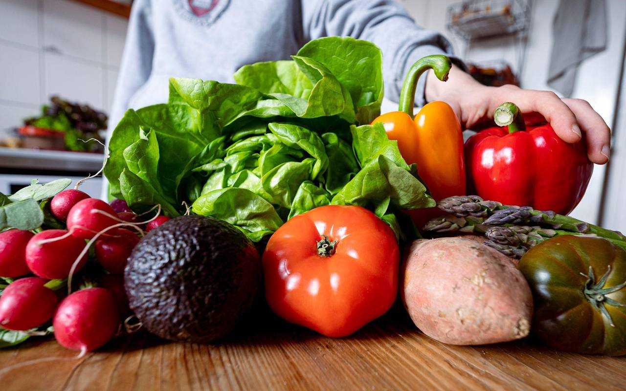 Eine Frau legt eine Paprika auf eine Ansammlung an Gemüse