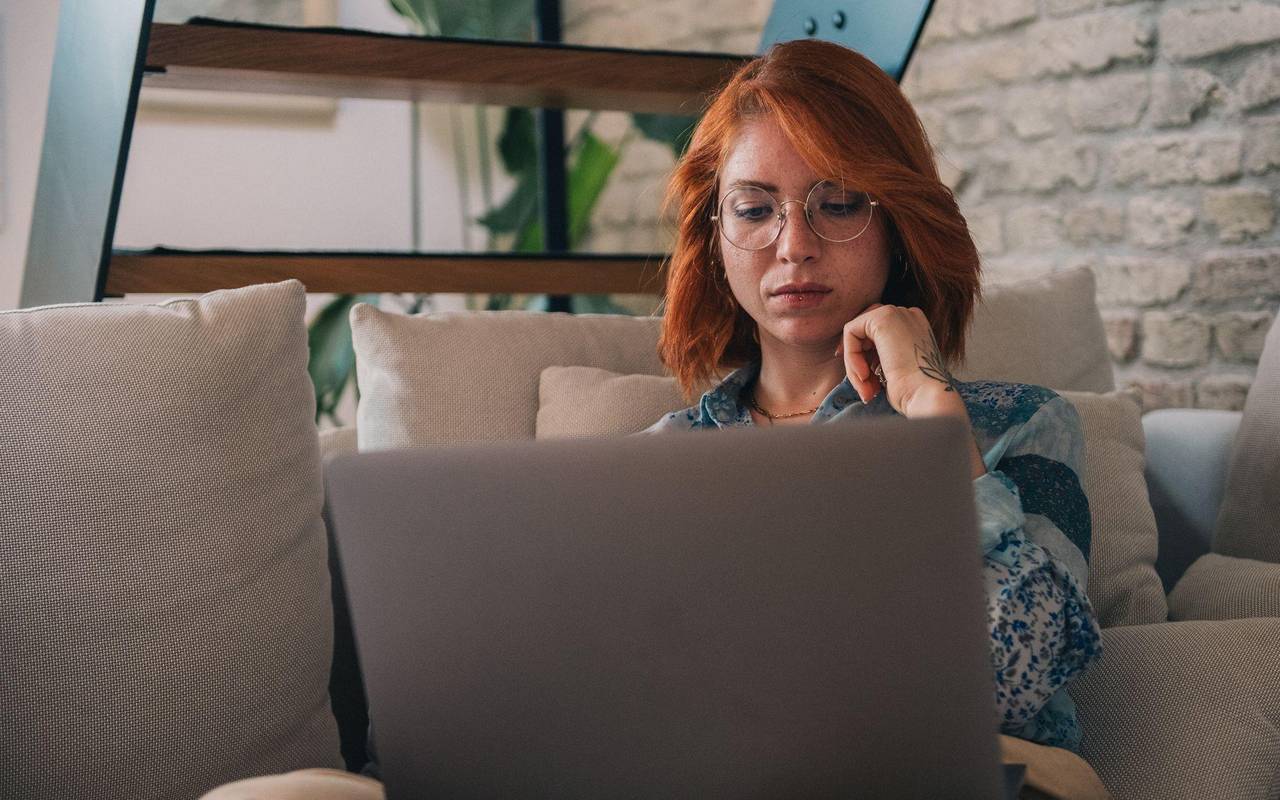 Frau schaut nachdenklich auf einen Laptop