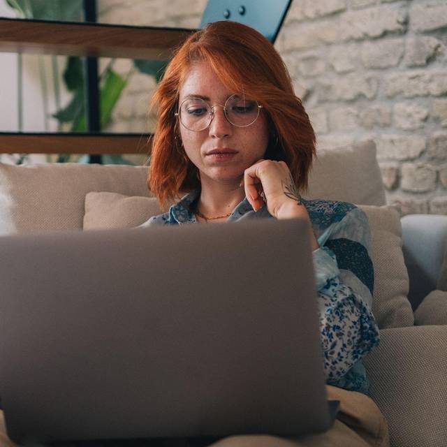 Frau schaut nachdenklich auf einen Laptop