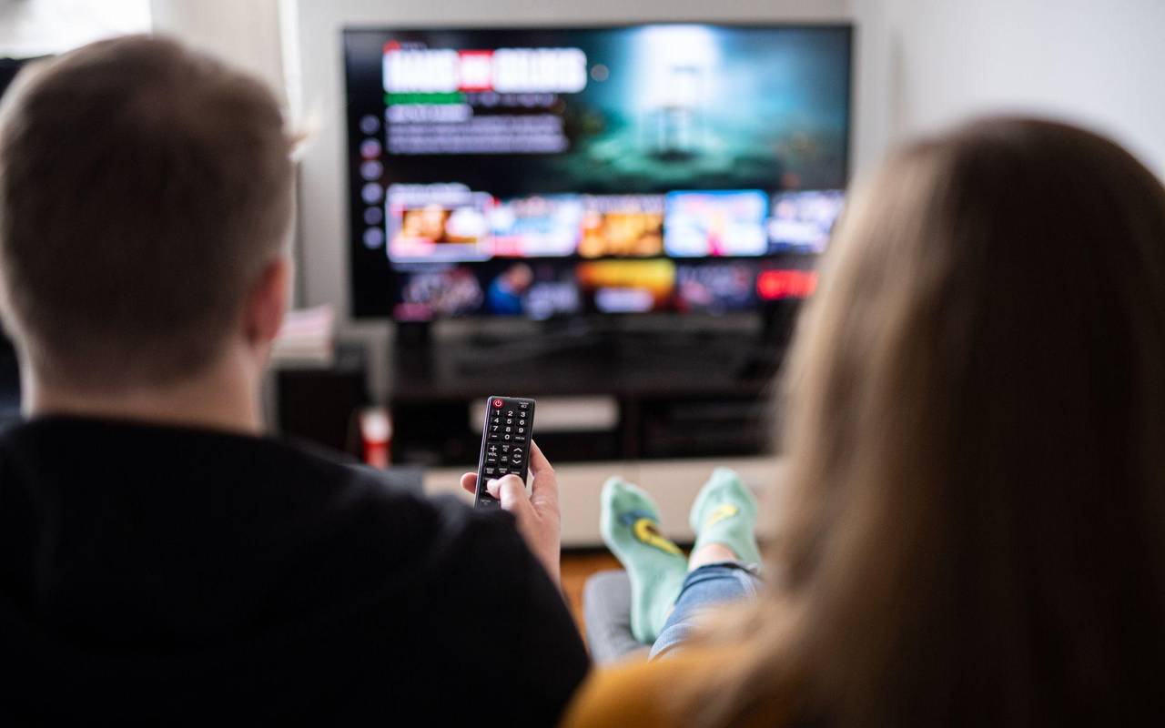 Paar sitzt vor einem Fernseher mit Streamingdiensten