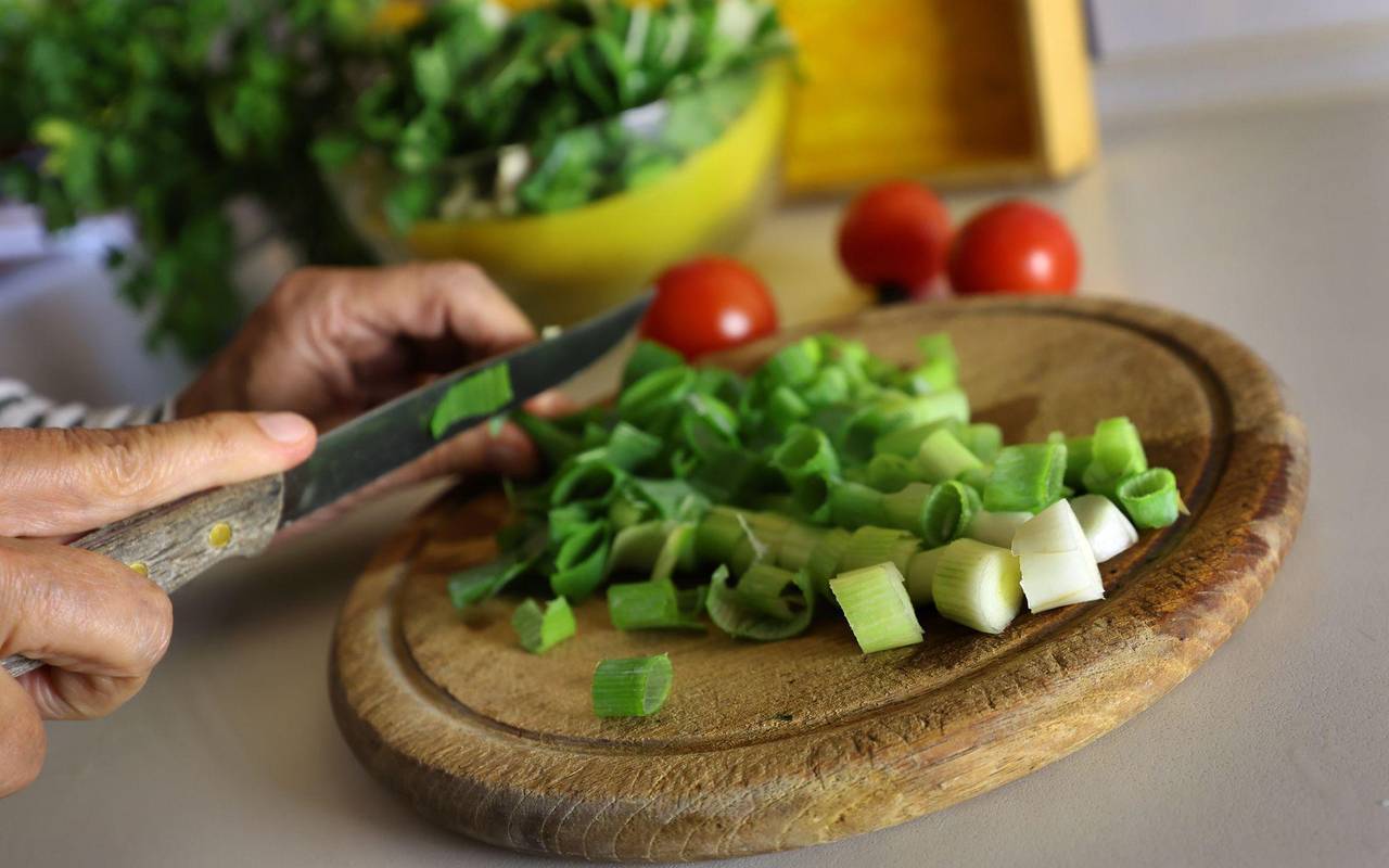 Eine Frau schneidet beim Kochen Lauchzwiebeln