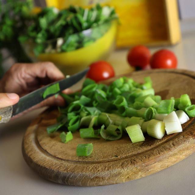 Eine Frau schneidet beim Kochen Lauchzwiebeln