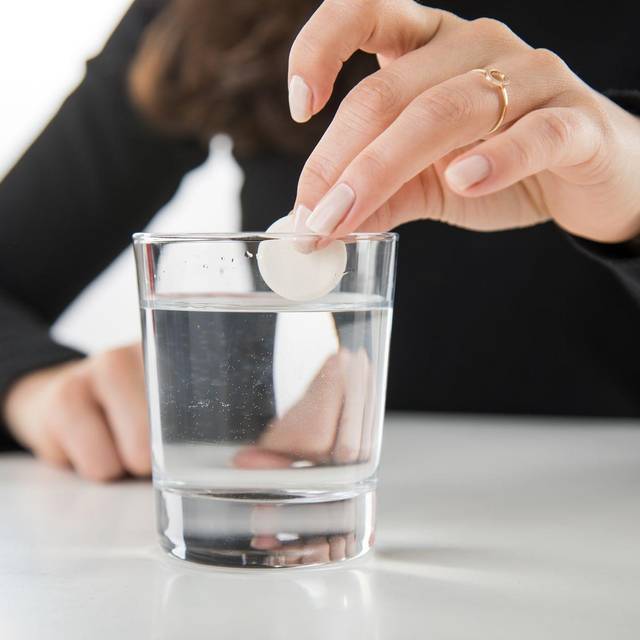 Brausetablette wird in ein Glas Wasser gegeben