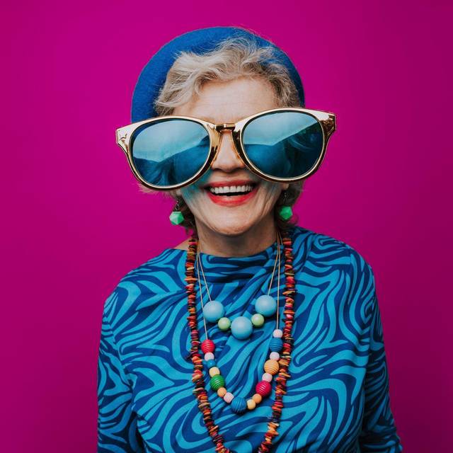 Eine glückliche Seniorin mit übergroßer Sonnenbrille