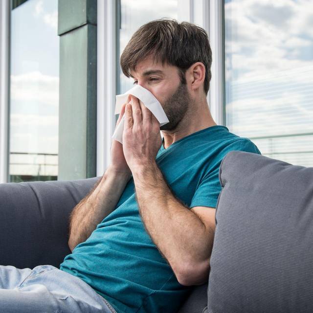 Ein Mann putzt sich die Nase