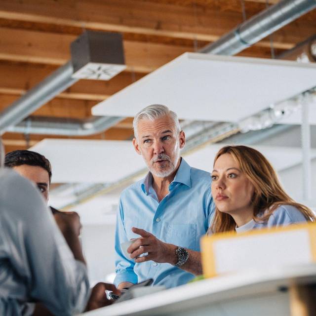 Eine Gruppe Kolleginnen und Kollegen an einem Stehtisch