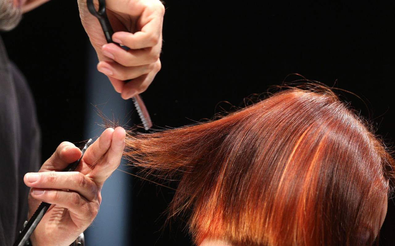 Ein Friseur schneidet einer Frau mit roten Haaren die Haare