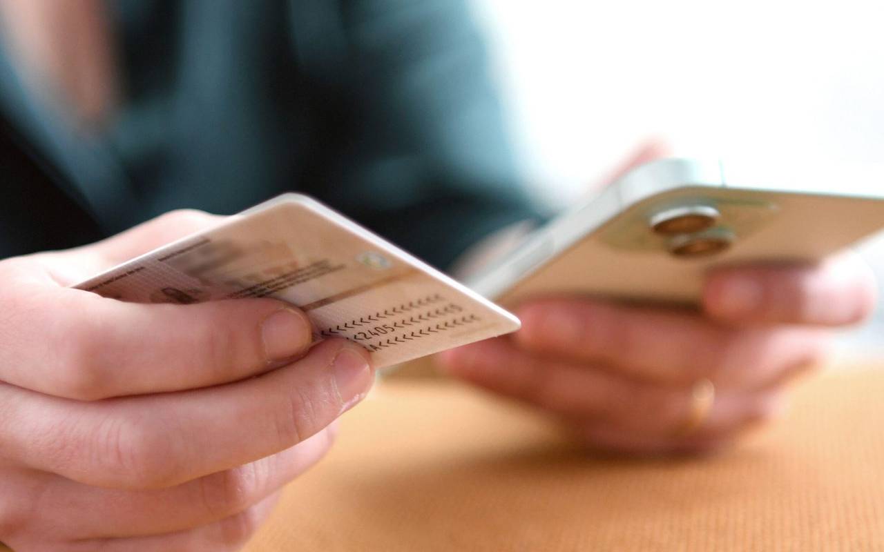 Eine Frau hält Personalausweis und Smartphone in den Händen