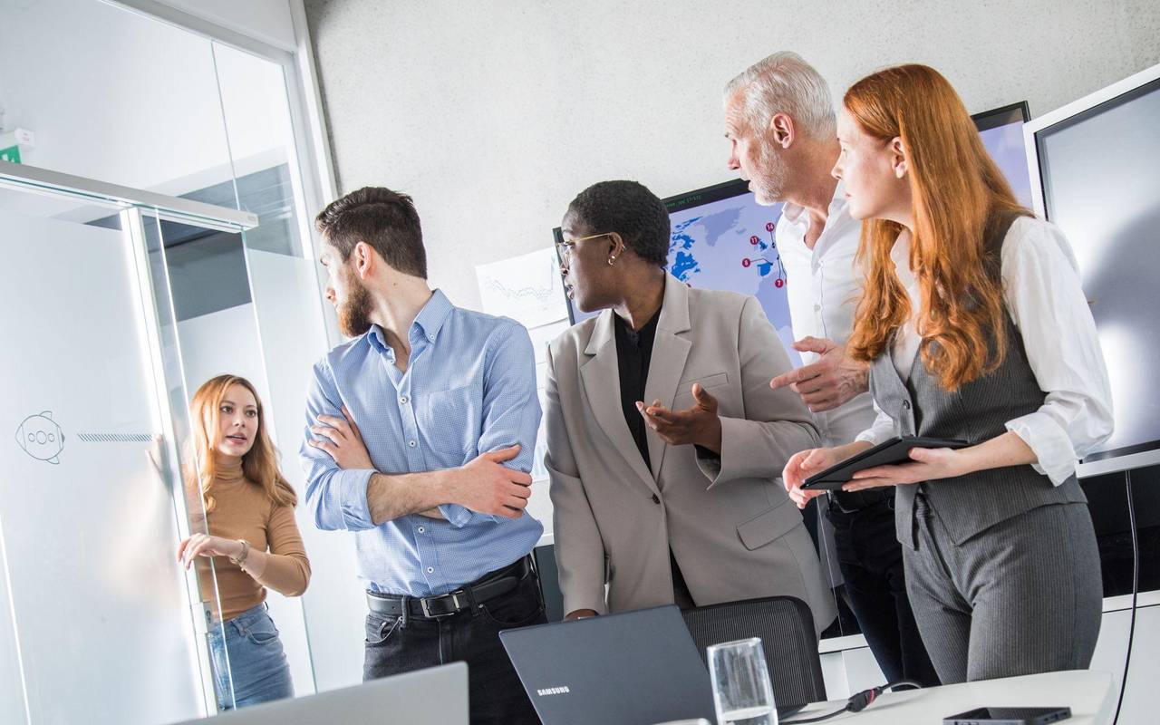 Eine Kollegin hebt die Uhr in einem Meeting mit anderen Kollegen