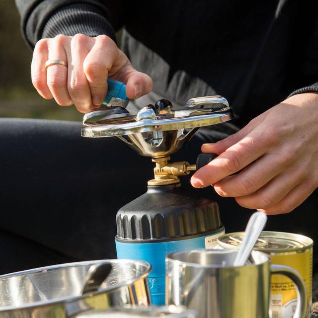 Frau bereitet Essen auf einem Campingkocher zu