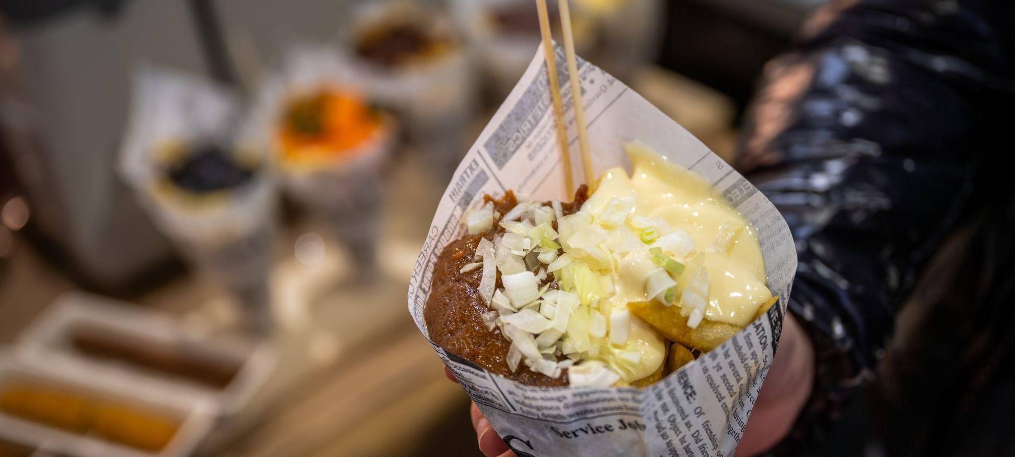 Eine Messebesucherin hält eine Tüte Pommes in der Hand